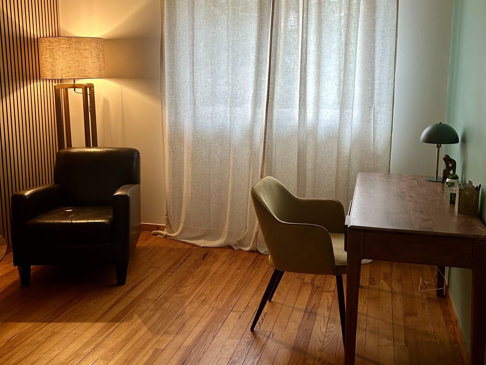 Le bureau du cabinet : fauteuil en cuir, lampadaire et fenêtre habillée de lin